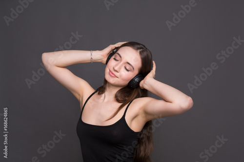 Woman listen to music in earphones, studio shot