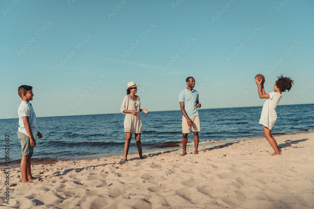 family playing with ball on beach