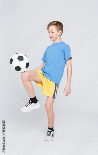 Fototapeta Naklejka Na Ścianę i Meble -  Boy in casual with soccer ball at white studio background
