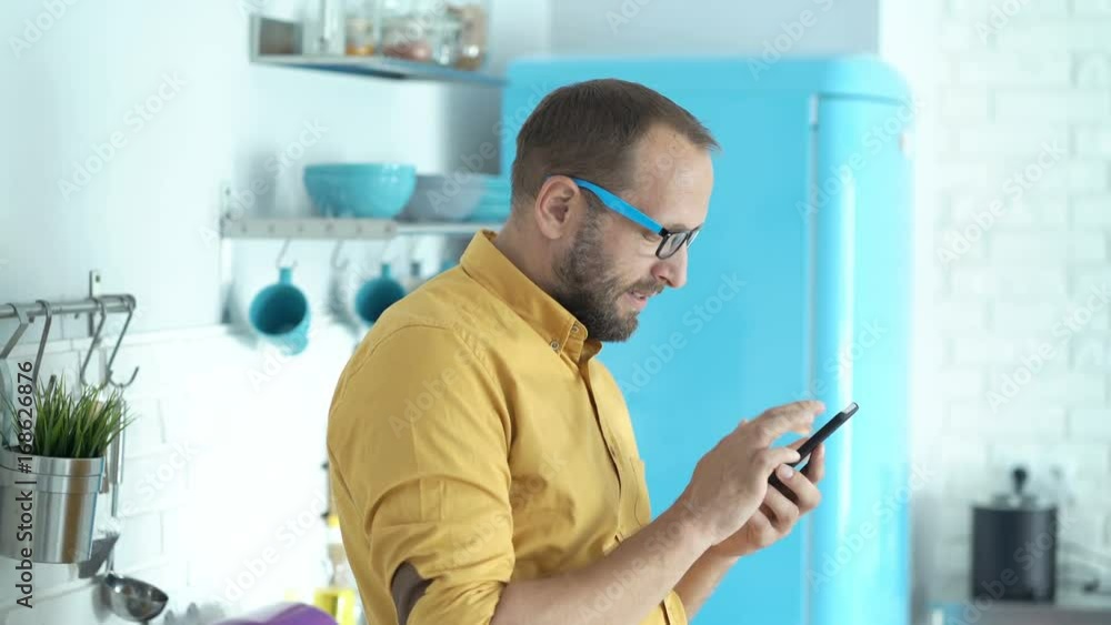 Young man texting on smartphone standing in kitchen at home
Young man texting on smartphone standing in kitchen at home