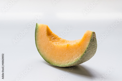 A slice of Rock Melon over white background.