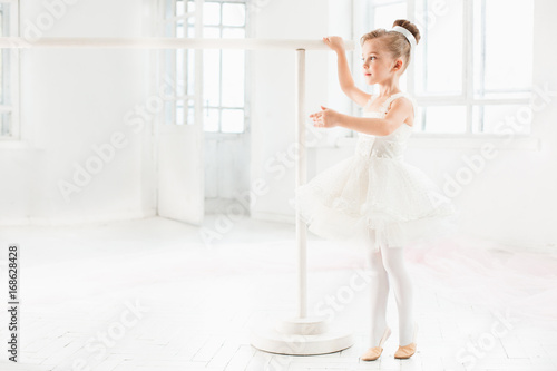 Little ballerina girl in a tutu. Adorable child dancing classical ballet in a white studio.