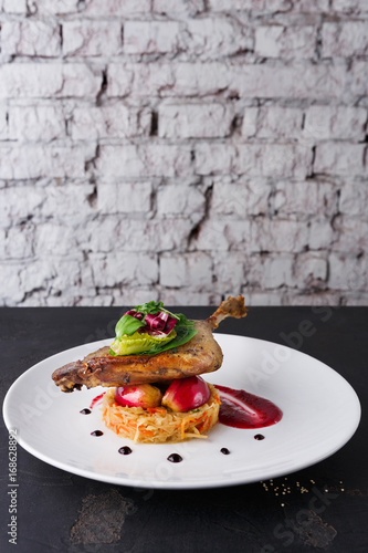 Restaurant meals. Duck confit with vegetables on black background