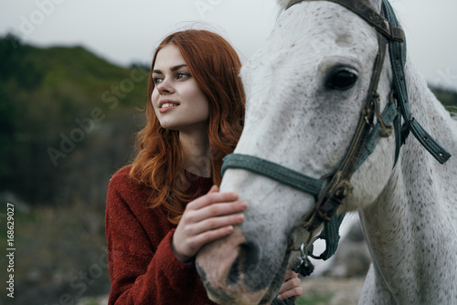 Beautiful young woman holding a white horse, portrait, mountains, nature