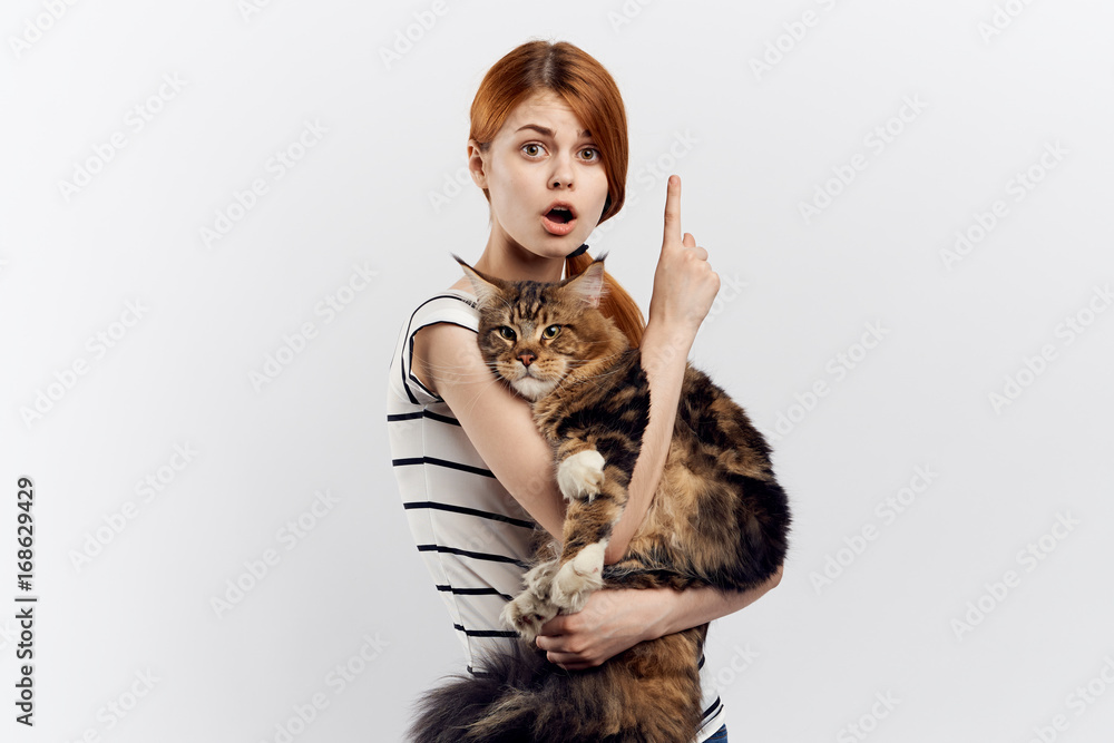 Beautiful young woman on a white background holds a cat, emotions, portrait, an allergy to pets