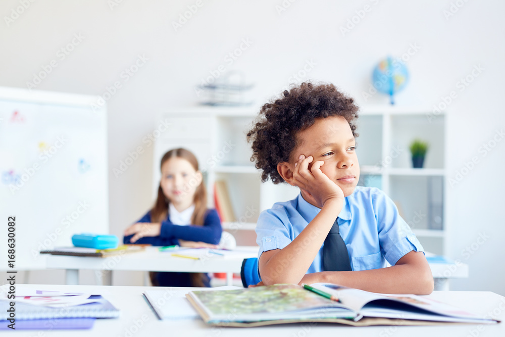African boy daydreaming at lesson of literature and looking through classroom window African boy daydreaming at lesson of literature and looking through classroom window