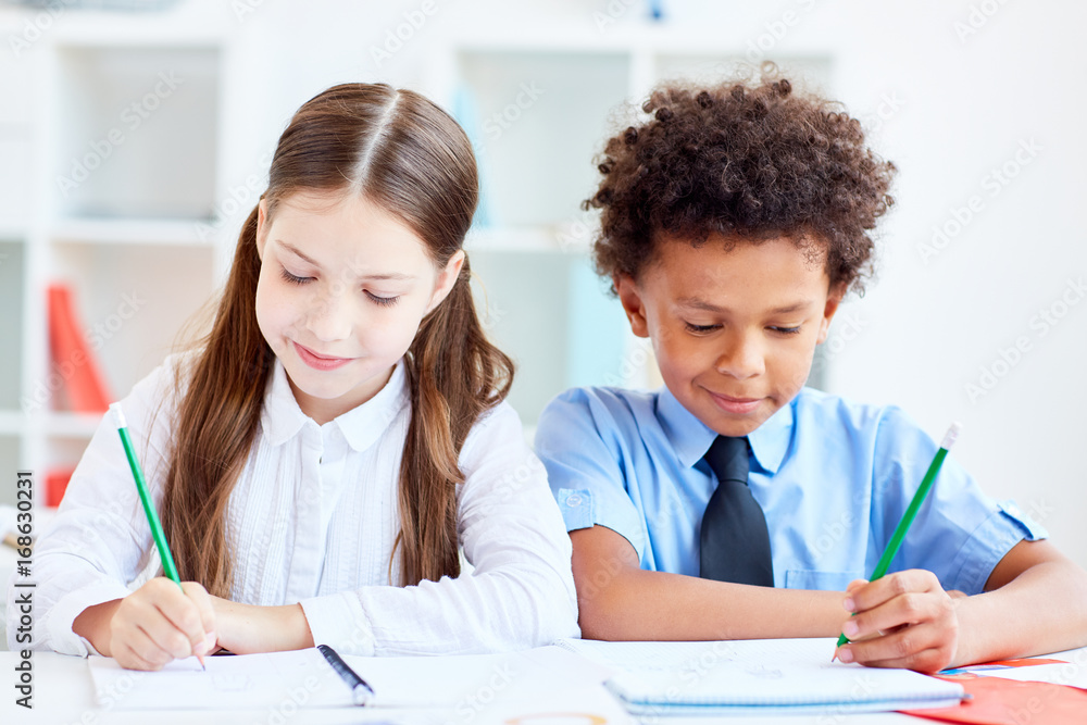 Two little classmates of elementary school drawing in copybooks Two little classmates of elementary school drawing in copybooks