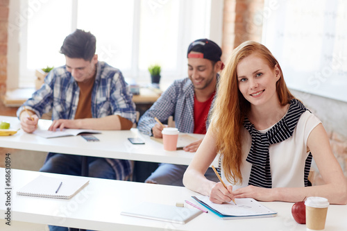 Young student carrying out task during final exam at college