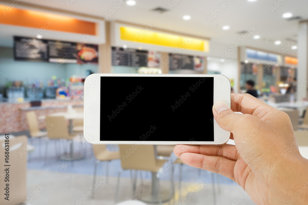 smart phone with abstract blur of food court background smart phone with abstract blur of food court background