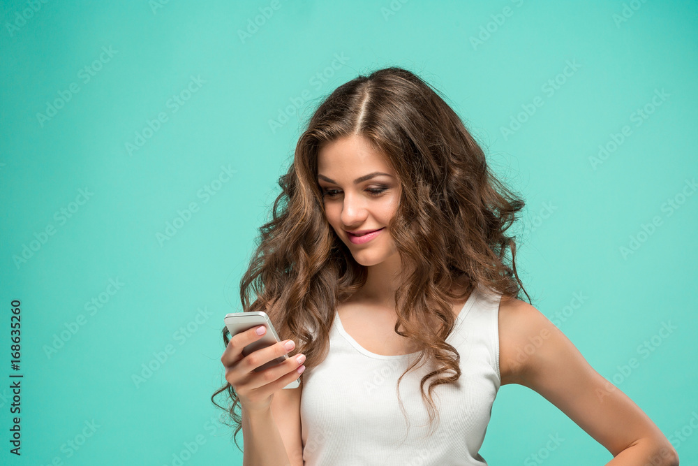 Shocked woman looking at mobile phone on green background Shocked woman looking at mobile phone on green background