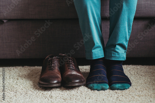 The man seats near shoes on the sofa