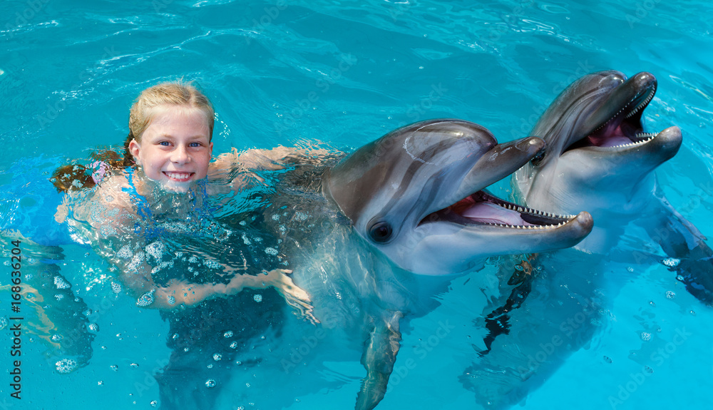 Obraz premium Happy child and dolphins in blue water. Dolphin Assisted Therapy