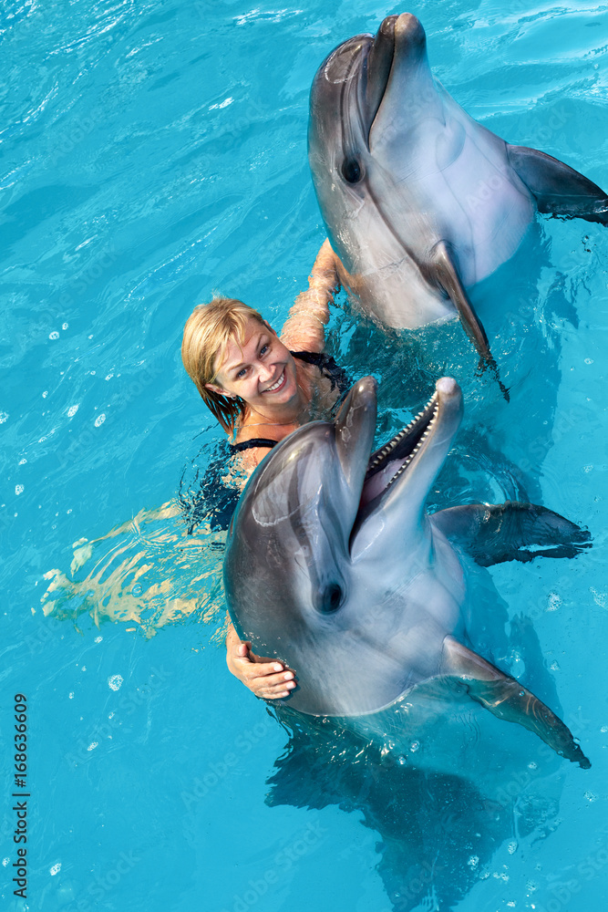 Fototapeta premium Coach swims in the water with dolphins. Dolphin Assisted Therapy.