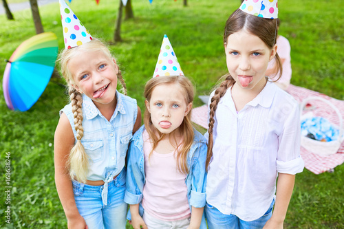 Obraz na plátně Funny girls showing their tongues and grimacing at birthday party