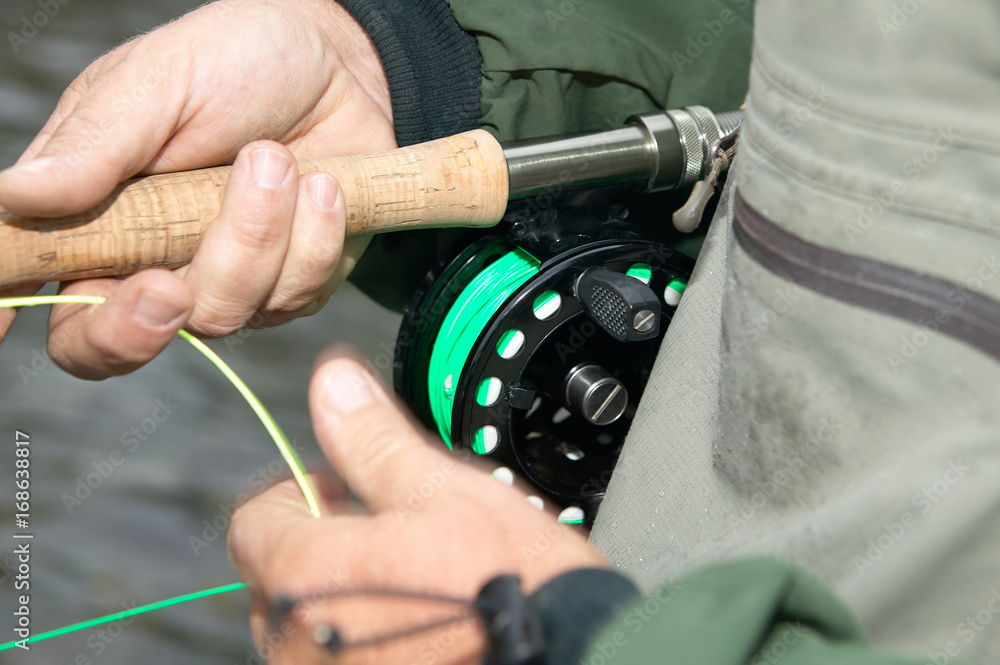 Close up of fly fisherman hands, reel and line