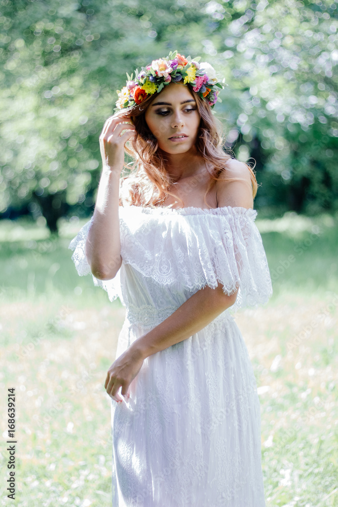 Fototapeta premium Bride in a wedding dress staying on the green forest.