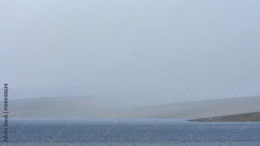 Obraz premium magnificent lake near sandy hill with white fluffy clouds in blue sky 
