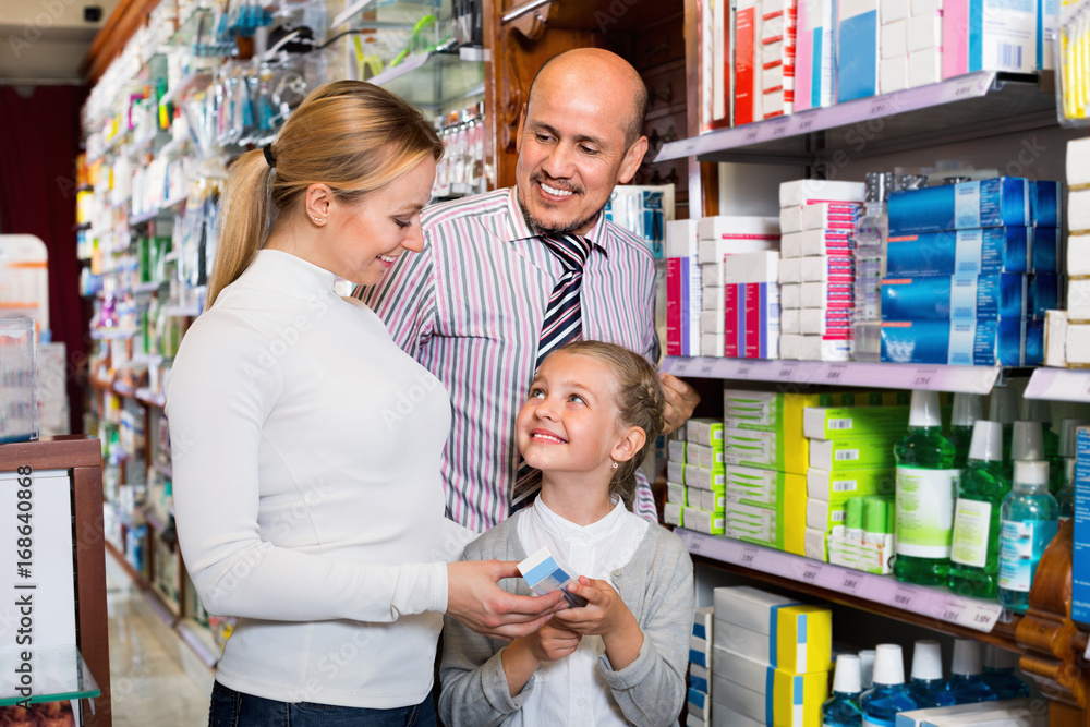 Mother and father with kid picking in pharmaceutical store