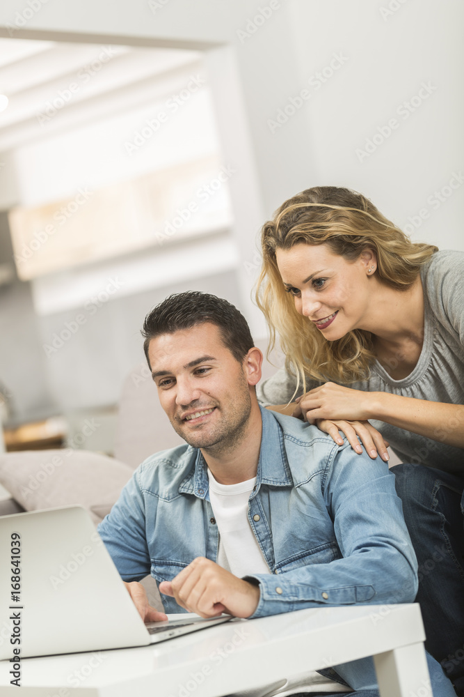 Happy young couple in their living room with a laptop Happy young couple in their living room with a laptop