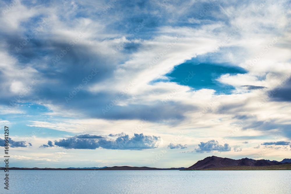 panoramic view of seascape with hills and fluffy clouds in morning sky
