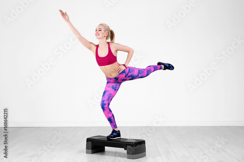 Fototapeta Naklejka Na Ścianę i Meble -  Young sporty woman training legs with stepper in gym