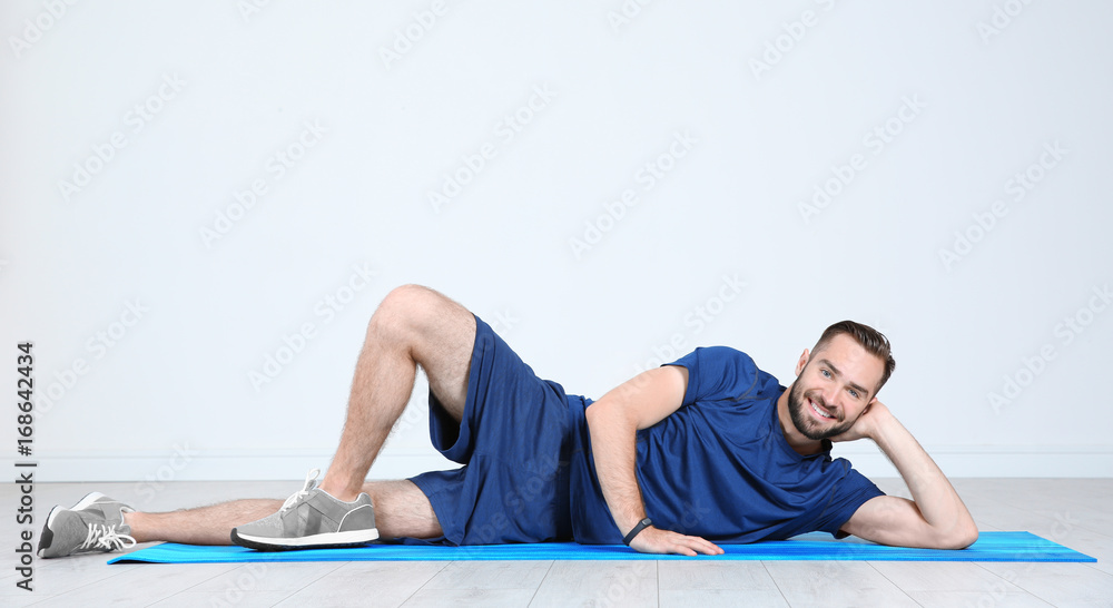 Sporty young man training legs on mat in gym Sporty young man training legs on mat in gym