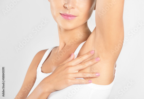 Beautiful young woman on light background. Concept of using deodorant photo