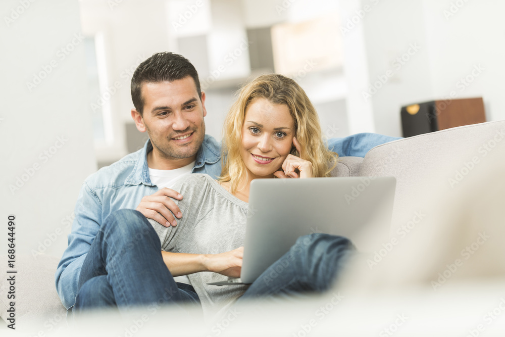 Happy young couple watching internet on their laptop Happy young couple watching internet on their laptop