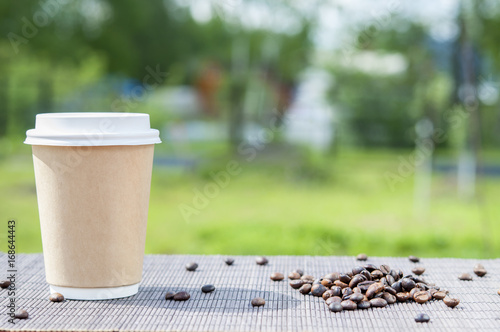 Paper Cup of coffee on a background of nature.