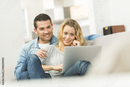 Happy young couple watching internet on their laptop
