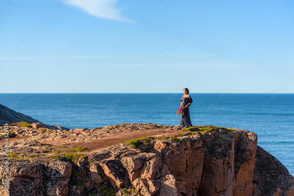 Girl in a dress on the edge of a cliff