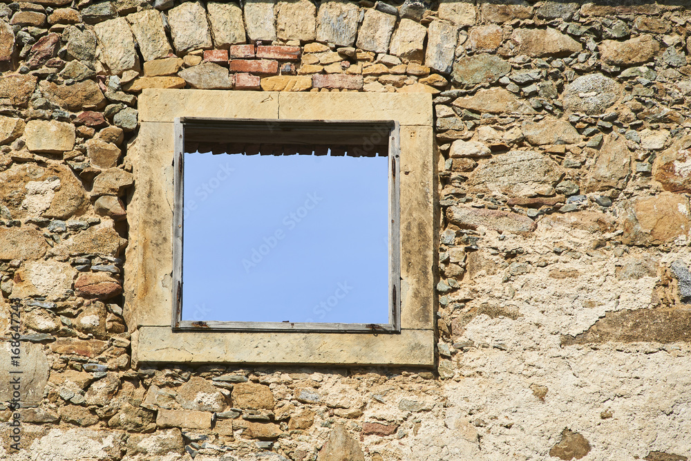 Blue sky visible through an old broken window in an abandoned building Blue sky visible through an old broken window in an abandoned building