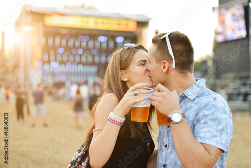 Couple kissing, drinking beer and having fun at music festival 