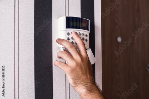Protection of the apartment and the house. Alarm and surveillance console. Apartment under protection. The man's hand puts the alarm