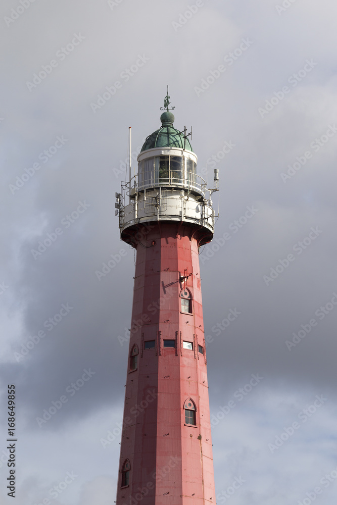 Lighthouse tower on cloudy sky background