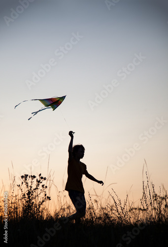 Fototapeta Naklejka Na Ścianę i Meble -  boy playing kite on summer sunset meadow silhouetted