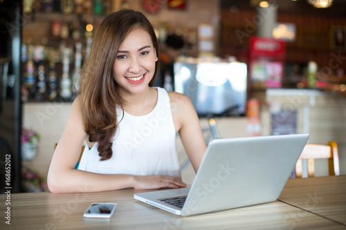 Young Asia woman sitting at cafe working on laptop and smart phone