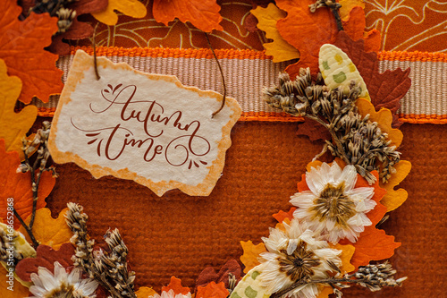 Autumn time calligraphy lettering text on beautiful autumn decor with leaves and tag