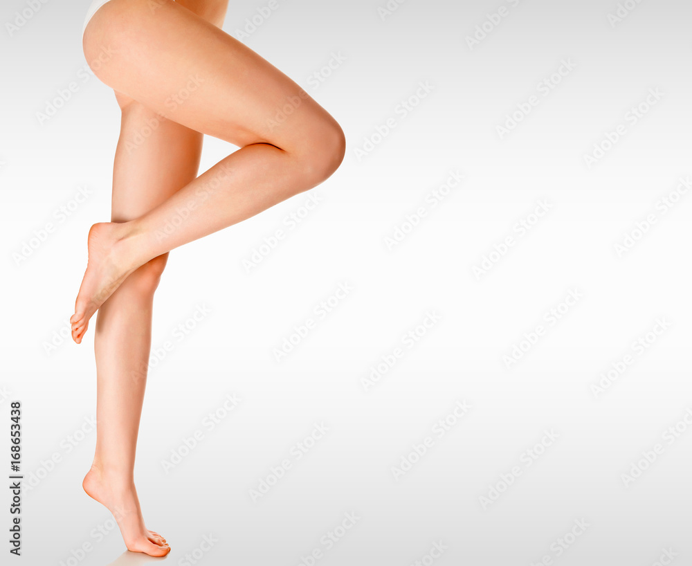 Long woman's legs against a grey background with copyspace
