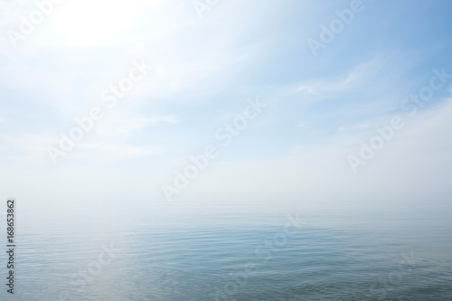 Fototapeta Calm tranquil blue sea with no waves and with foggy backgroudn