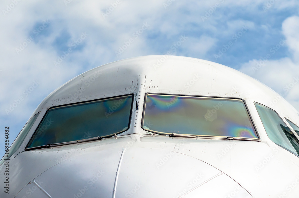 Fototapeta premium Passenger airplane nose cockpit in blue clouds sky