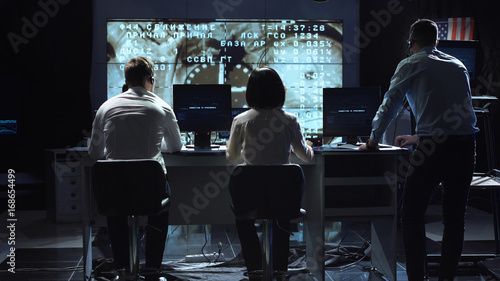 Back view of people working and managing flight in mission control center. Docking to the international space station in space. Elements of this image furnished by NASA. photo