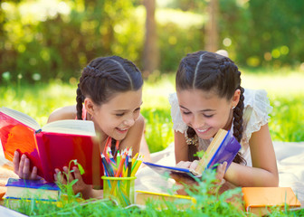 Happy hispanic girls drawing and studying in park