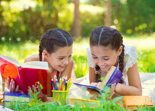 Happy hispanic girls drawing and studying in park