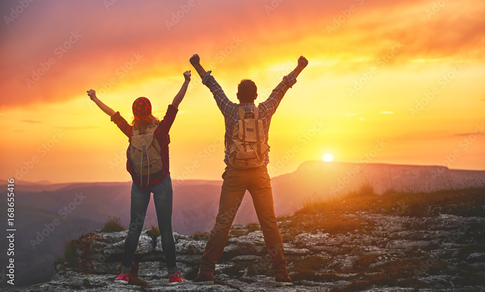 Fototapeta premium happy couple man and woman tourist at top of mountain at sunset a hike in summer