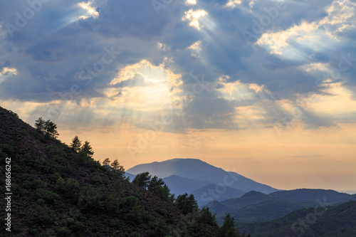 Mediterranean mountains during sunset with sun rays and pine tree silhouettes