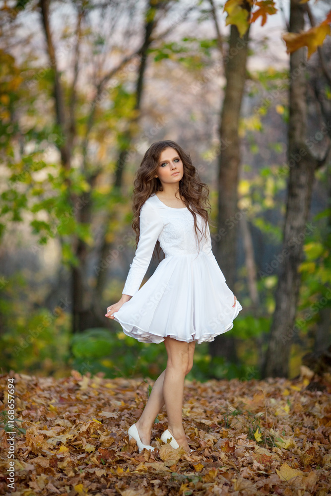 Beautiful young girl with makeup and hair-dress on a background of autumn forest