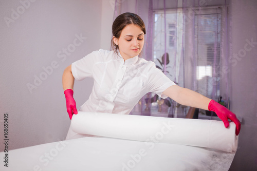 Bilde på lerret The cosmetologist carefully covers the cosmetology couch