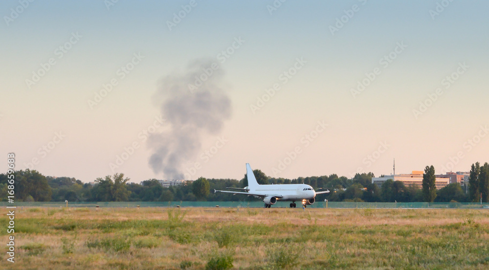 Fototapeta premium Smoke near airport with airplane taxiing on runway