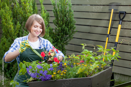 Young smiling woman florist working in the garden.